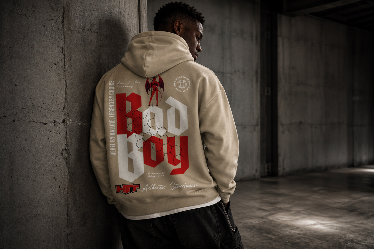 Male model wearing HTT BadBoy Heavy Hoodie Sand in an industrial streetwear setting