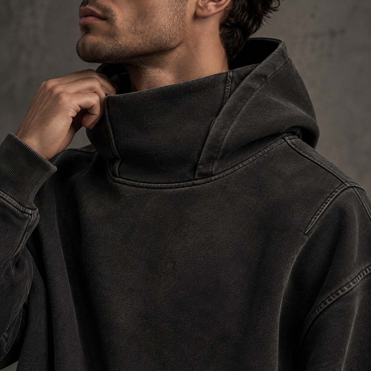 Nahaufnahme der hochgeschnittenen Rollkragenkapuze und des verwaschenen schwarzen Stoffes des HTT Blanks-Hoodies