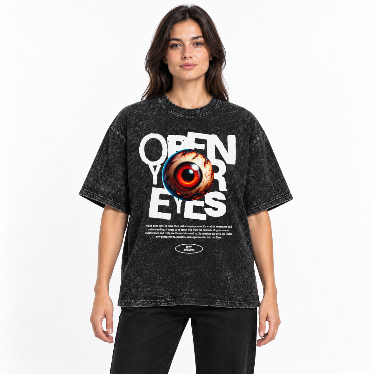 Vrouw draagt het HTT Open Your Eyes oversized T-shirt in washed black met witte tekstprint en rood oog tegen een lichte studioachtergrond.