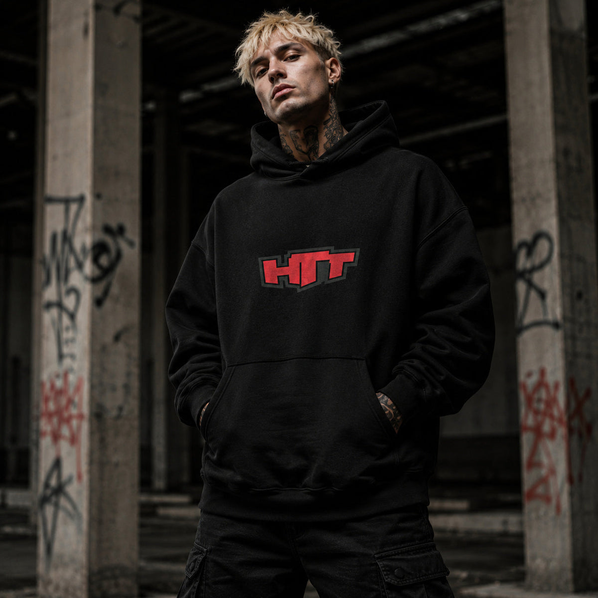 Sudadera con capucha HTT Urban Chaos negra, llevada por un modelo rubio de streetwear; vista frontal con el logotipo rojo de HTT